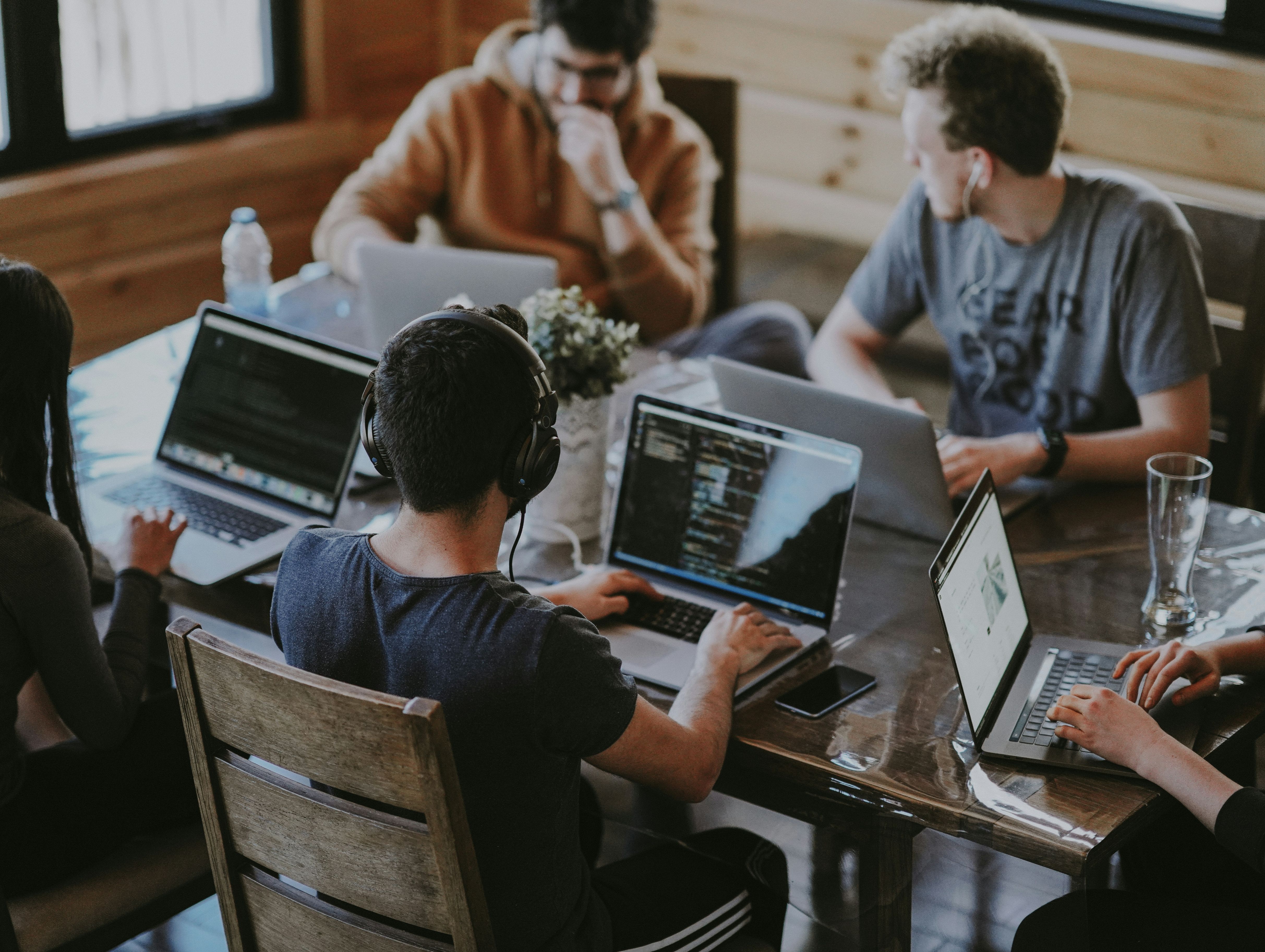 Mehrere Menschen sitzen vor PC am Tisch und arbeiten gemeinsam