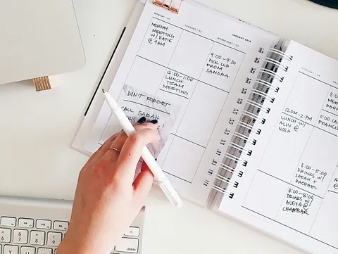 Hand liegt auf einer Tastatur und schreiben einen Termin in den Kalender
