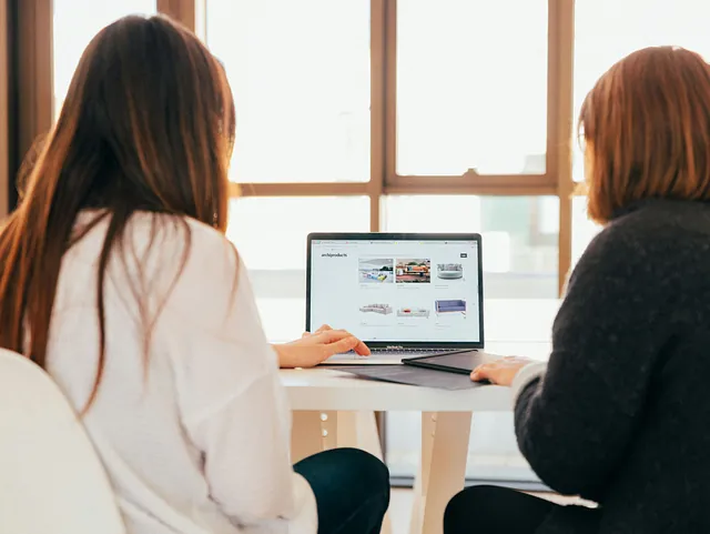 Zwei Frauen sitzen in einem Beratungsgespräch vor einem Laptop